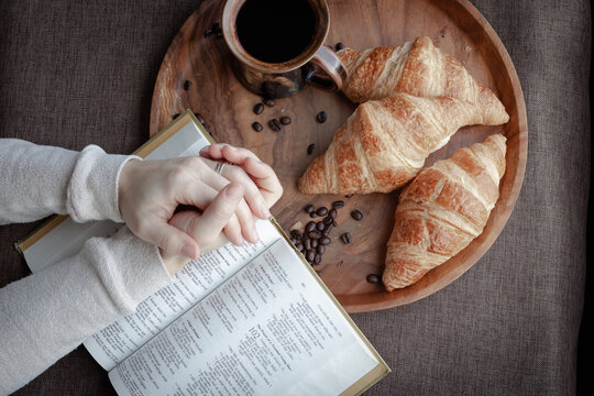 hands in prayer with bible, coffee and croissants