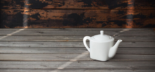 Fototapeta na wymiar White empty porcelain teapot on gray vintage wooden background