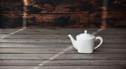 Fototapeta na wymiar White empty porcelain teapot on gray vintage wooden background
