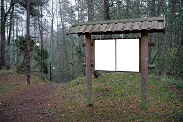 Board with information in front of the forest path. Mock up in the forest.