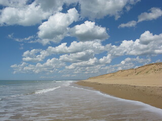 Fototapeta na wymiar Pieds dans l'eau sur une plage de Vendée avec nuages moutonnant sur l'horizon (vue latérale) 1