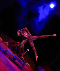twins acrobats in neon costumes stand on their arms, ultraviolet makeup