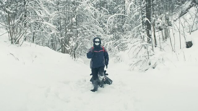 Rescue robot in a plastic mask, black glasses drags stretcher with an injured person through snow. Concept of parody, cyberpunk and post apocalyptic
