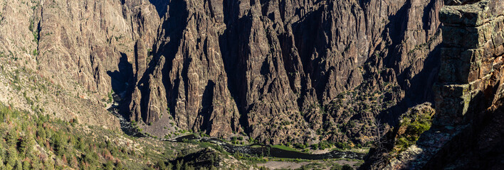 Panorama shot of gunnison river and rocky walls in black canyon of gunnison at sunny day in america