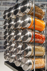 A metal spice rack with many glass bottles filled with different spices
