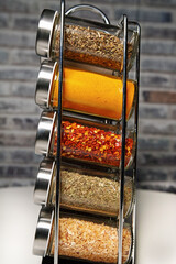 A metal spice rack with many glass bottles filled with different spices