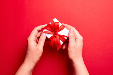 Hands holding gift box on red background