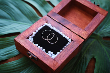 silver wedding rings in a wooden box decorated with pearls. vintage background