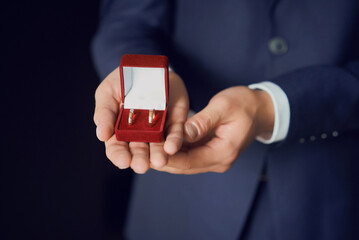 golden wedding rings in a red gift box and a bridal bouquet made of white roses. close-up, macro