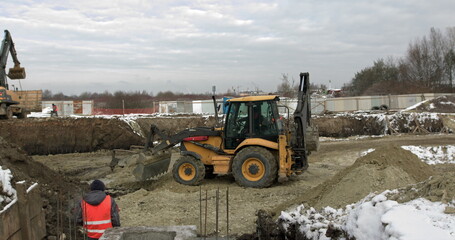 Loader excavator, bulldozer and roller work on construction site. Machines perform excavation work. Compaction of soil and rubble for residential buildings. Construction work