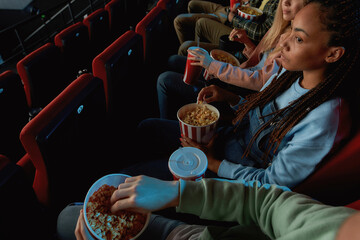High angle view of friends holding baskets of popcorn while watching movie together at the cinema