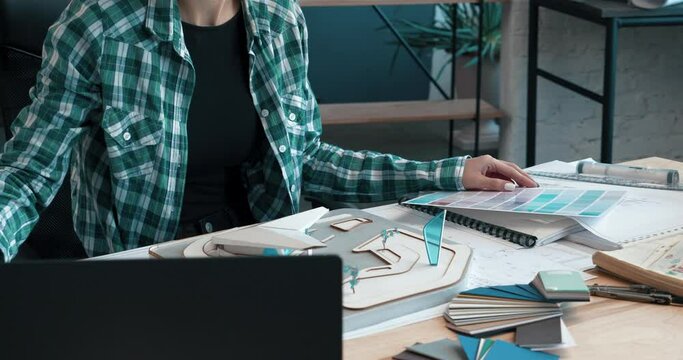 Young Woman Assistant writing Notes about the Design of Interior New Building.Wearing casual clothes and stylish glasses at modern office.