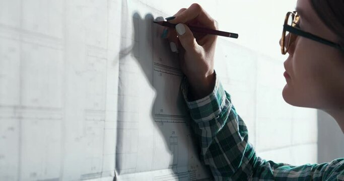 Confident Woman - Engeneer drawing on desk Project of New Shopping Centre. Wearing a Casual Look. Satisfied of her Profession.