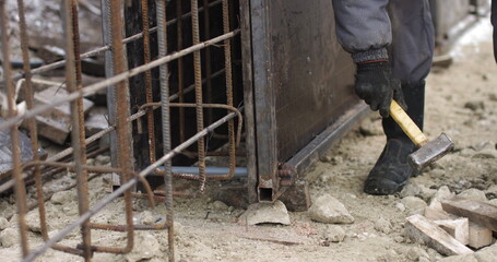 Engineers work with metal constructions while building a house. The worker fixes the form for pouring concrete, aligns metal boards. Filling the foundation of the building