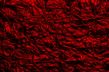 Red foil background with shiny crumpled surface for texture background. Iridescent surface wrinkled foil