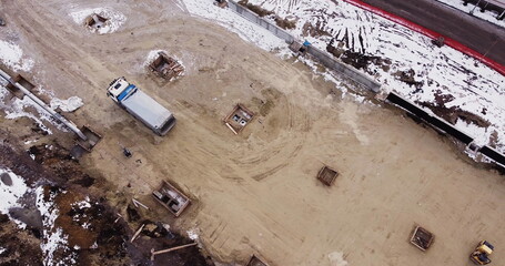 Aerial view of heavy machinery, Articulated truck moving dirt on a new road construction site, heavy equipment top down footage of dump truck