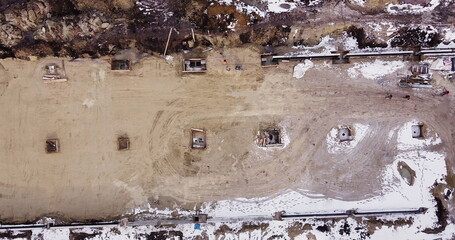 Top to bottom view of contractors in protective caps. Aerial flight over a new construction site with heavy machinery and people building real estate. Filling the foundation of the building. Top to