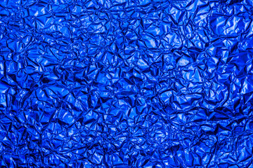 Bright blue foil background with shiny crumpled surface for texture background. Iridescent surface wrinkled foil