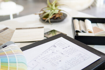 Interior designer's working table, an architectural plan of the house, a color palette, furniture and fabric samples. Drawings and plans for house decoration.