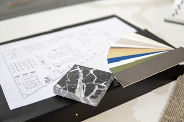 Interior designer's working table, an architectural plan of the house, a color palette, furniture and fabric samples. Drawings and plans for house decoration.