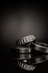 Car bearings, auto parts, steel automotive bearings, placed on black reflective surface, on black...
