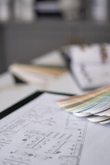 Interior designer's working table, an architectural plan of the house, a color palette, furniture and fabric samples. Drawings and plans for house decoration.