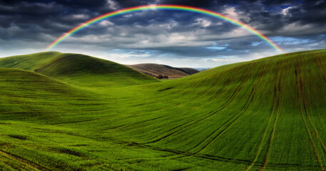 
Scenic view of rainbow over green field. dramatic gray sky over a picturesque hilly field
