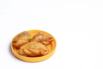 A Thai snack called (fluffed stuffed with fried fish) is placed in a plastic packaging lid on a white background. Close-up view.