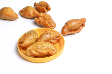 A Thai snack called (fluffed stuffed with fried fish) is placed in a plastic packaging lid on a white background. Close-up view.