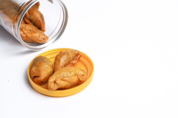 Thai snacks, named (Crispy, stuffed with fried fish), are placed in a plastic container lid on a white background, view on the left.