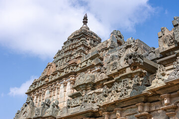 Fototapeta premium Lakkundi, Karnataka, India - November 6, 2013: Brahma Jinalaya temple. Vertical shot of vimanam on sanctum against blue cloudscape. Abundance of sculptures.