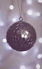 Christmas Holiday Background decorated with a silver bauble with bokeh lights behind.