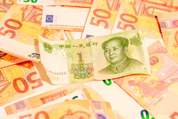 Fifty euro money banknotes background texture and Mao Zedong portrait on 1 Chinese paper currency Yuan renminbi in close up
