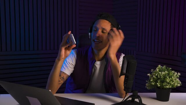 Multi-ethnic guy reviewing a smartphone and talking about it with smile. Blogger make selfshot in the studio.