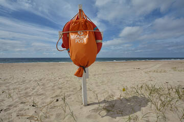 Life ring and orange sack on a wooden post on a lifeguard post (original Danish: "Rednings Post") on the North Sea beach of Nymindegab Strand, Denmark.