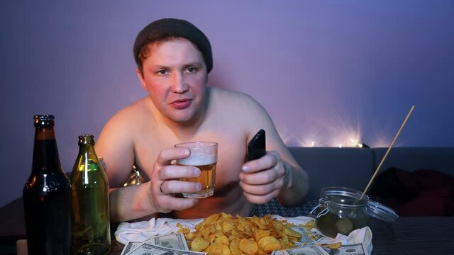 The peasant switches TV channels and eats pickles cucumber