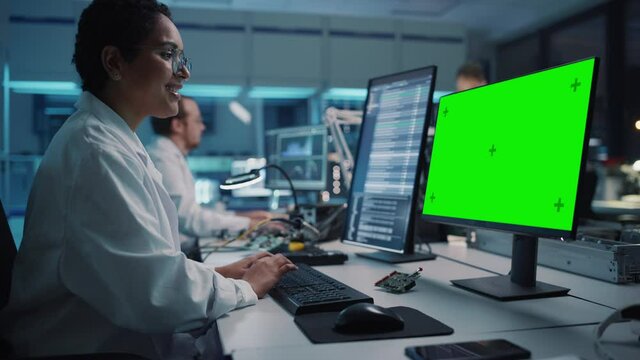 Modern Electronics Facility: Female Scientist, Engineer Works on Mock-up Green Chroma Key Screen Computer. Design, Development of Industrial PCB, Silicon Microchips, Semiconductors, Equipment