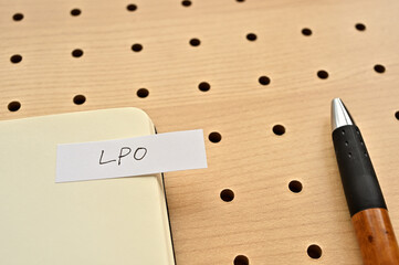 A sticky note with LPO written on the edge of an open notebook on the punching board. That's an...