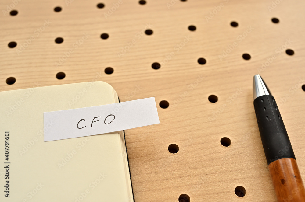 Poster a sticky note with cfo written on the edge of an open notebook on the punching board. that's an acro