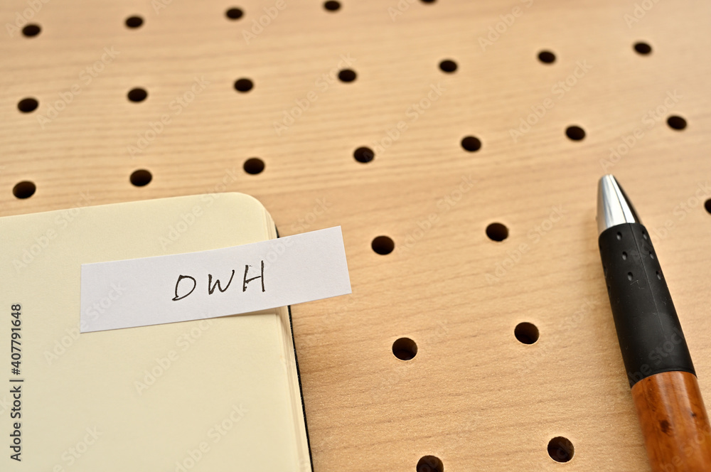 Aufkleber a sticky note with dwh written on the edge of an open notebook on the punching board. that's an acro