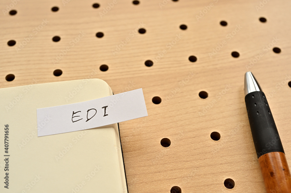 Poster a sticky note with edi written on the edge of an open notebook on the punching board. that's an acro