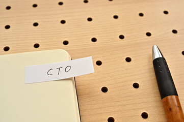 A sticky note with CTO written on the edge of an open notebook on the punching board. That's an acronym for chief technical officer.