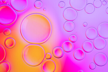 Creative neon background with drops. Glowing abstract backdrop with vibrant gradients on bubbles. Lilac, orange and pink overflowing colors.