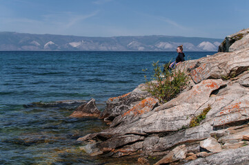 Fototapeta na wymiar Woman on a rocky shore near the water of Lake Baikal