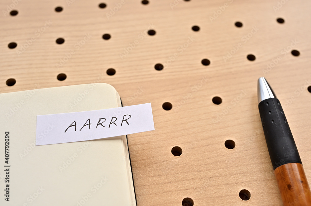 Poster a sticky note with aarrr written on the edge of an open notebook on the punching board. that's an ac
