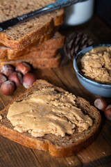 Slices of bread with homemade hazelnut spread and glass of milk on wooden table.  Homemade Hazelnut Butter. 