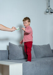 Little boy takes money from a man hand. Little boy stands on the bed and takes money from a man. 