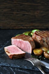 grill filet mignon and vegetables, grilled - young potatoes and peppers. steak mignon from the meat of young beef is shown in section, the degree of preparation is 