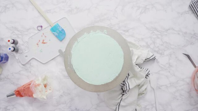 Step by step. Piping buttercream rosettes on top of round three-layer vanilla cake.