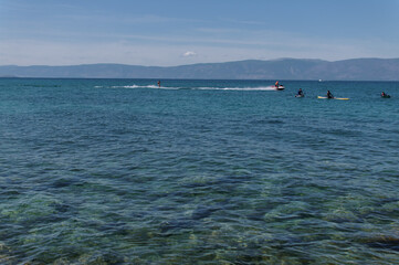 People on sap surfing and man on the water ski on the water of Lake Baikal